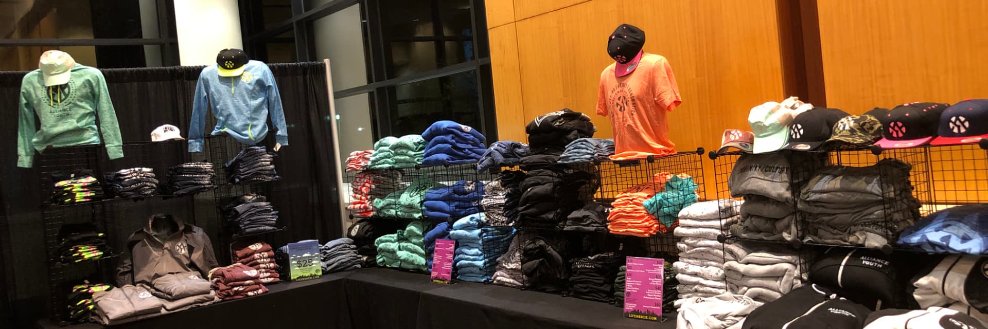 Custom printed tees, hoodies and hats on a retail display table by Hardiewear