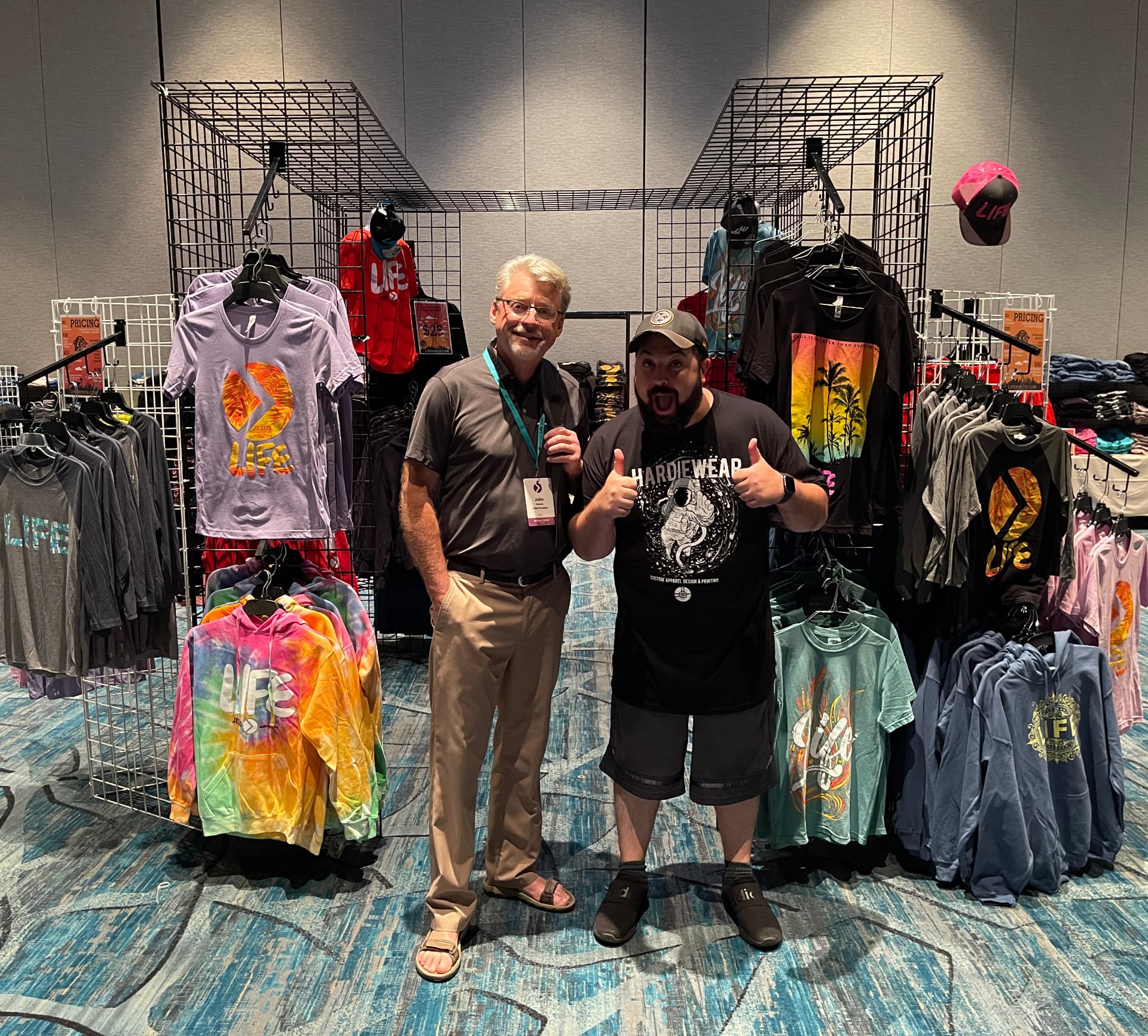 Branded merch booth with custom printed tees hanging on display by Hardiewear