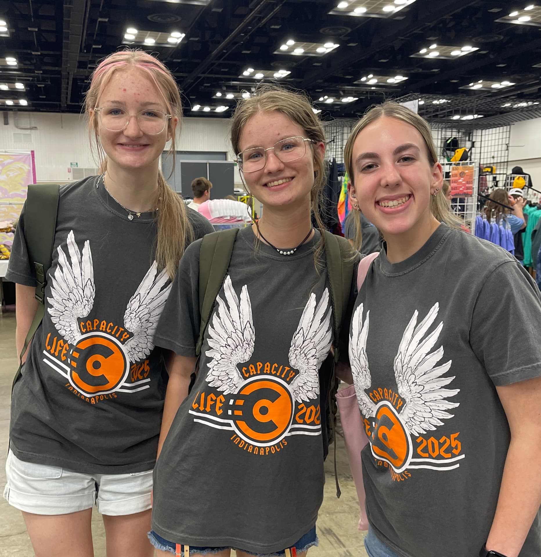 Three girls wearing custom printed event tees with a winged logo by Hardiewear