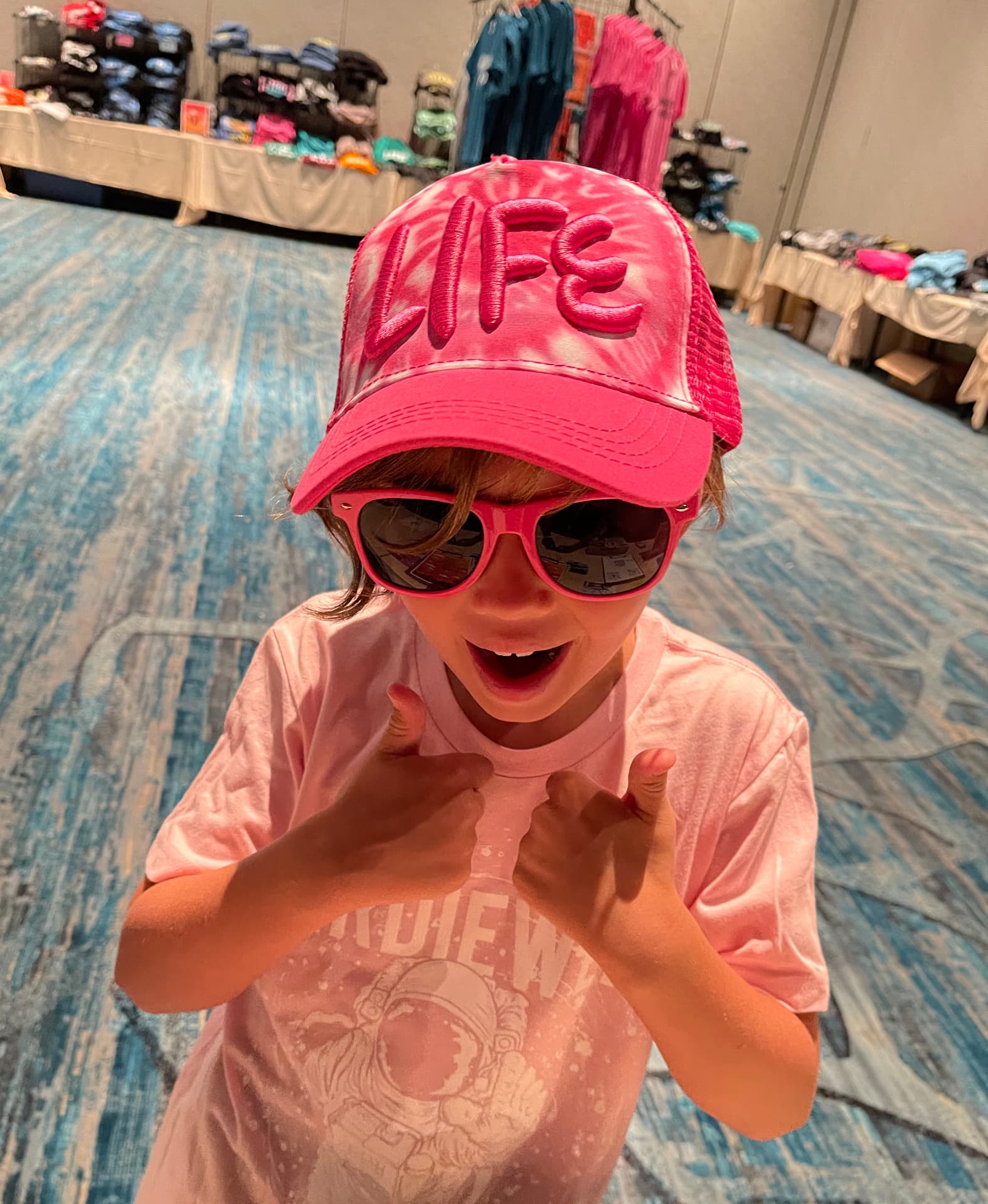 Young girl in a pink custom printed tee and embroidered trucker hat by Hardiewear